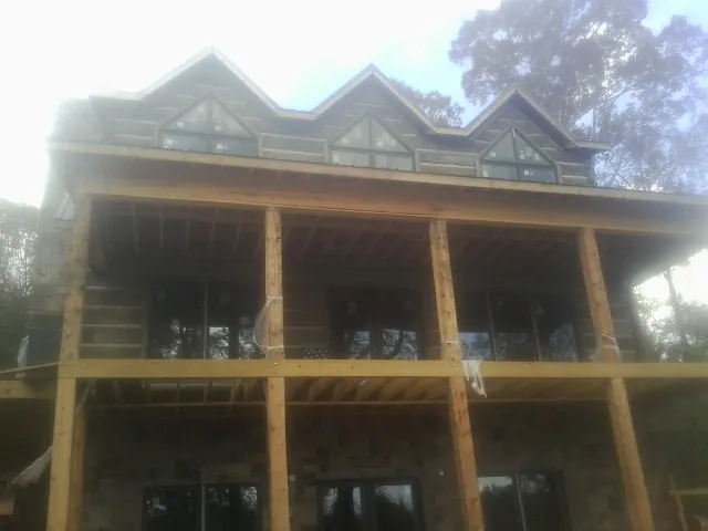 Dormers and porch framing on a large log home under construction — Roof Coating work by our crew in Bentleyville