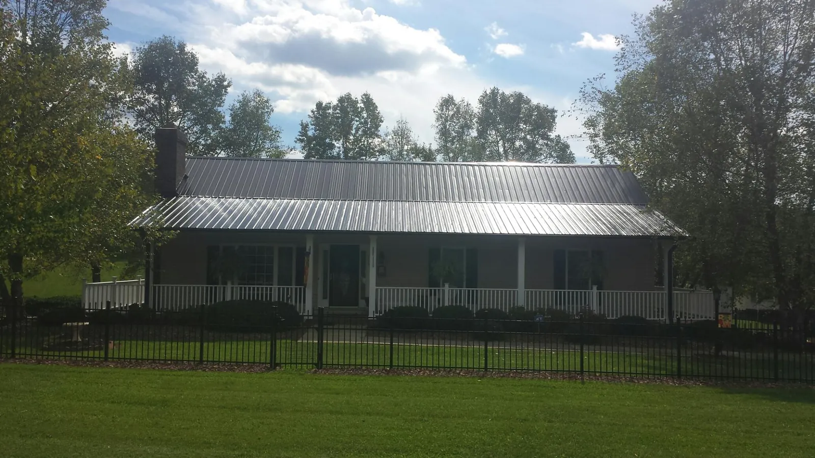 Gray metal roof on a brick ranch with a full width front porch — Gutter Guard Installation work by our crew in Bentleyville