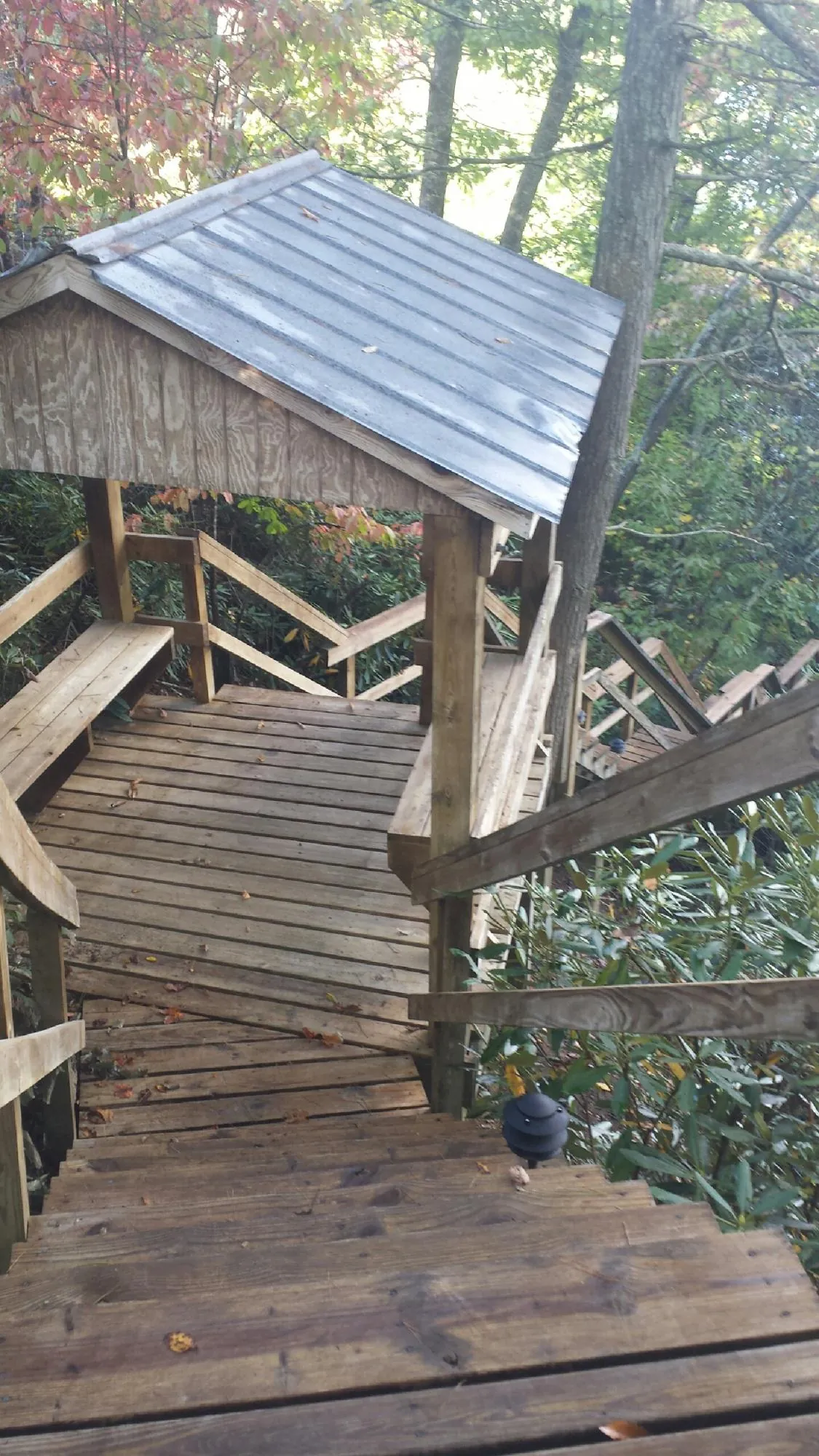 Metal roofed shelter over wooden steps on a wooded walkway — Skylight Repair & Installation work by our crew in Bentleyville