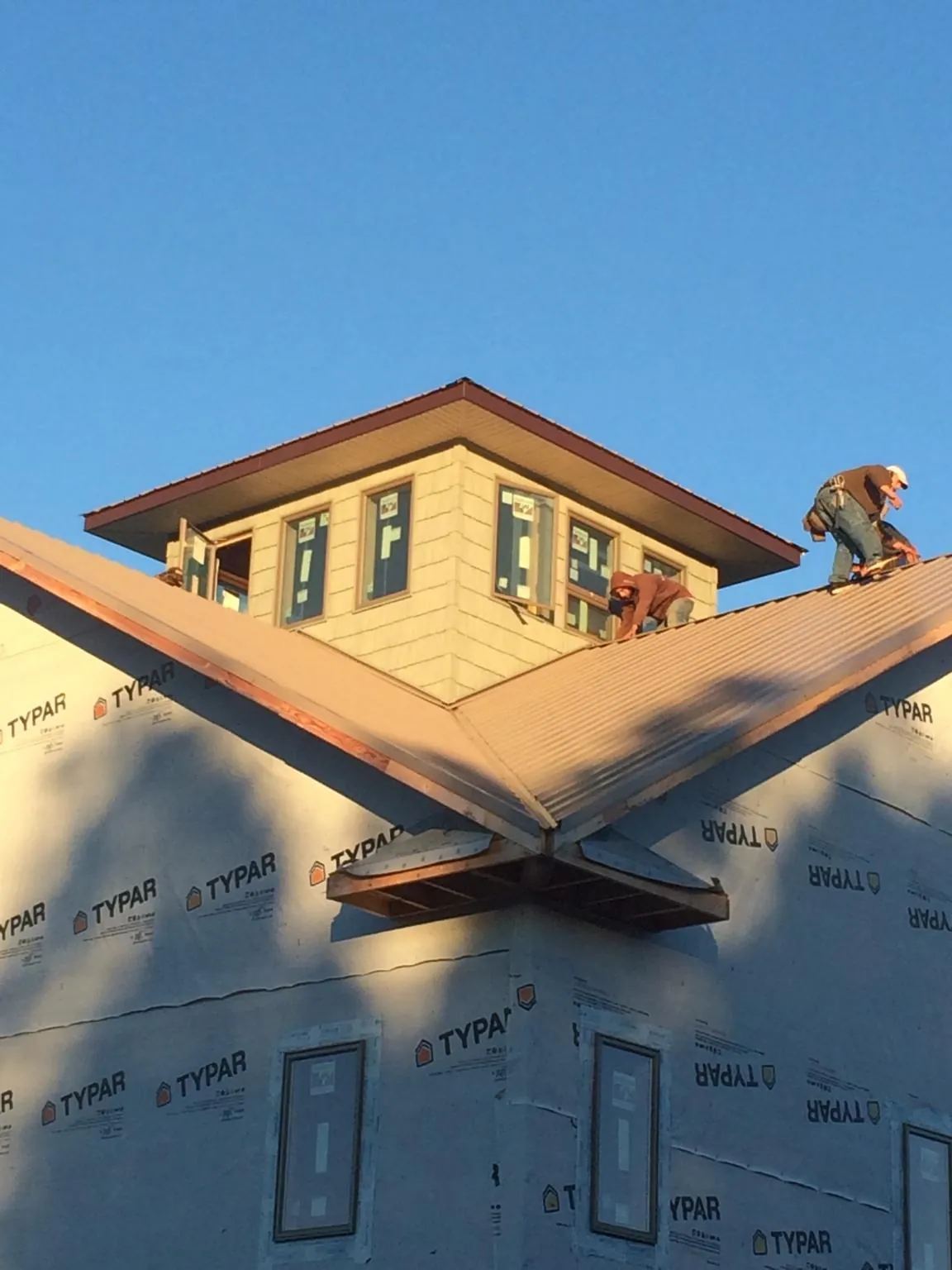 Roofers working around a rooftop cupola on a new metal roof at sunset — Roof Waterproofing in Bentleyville by Roofing Brothers